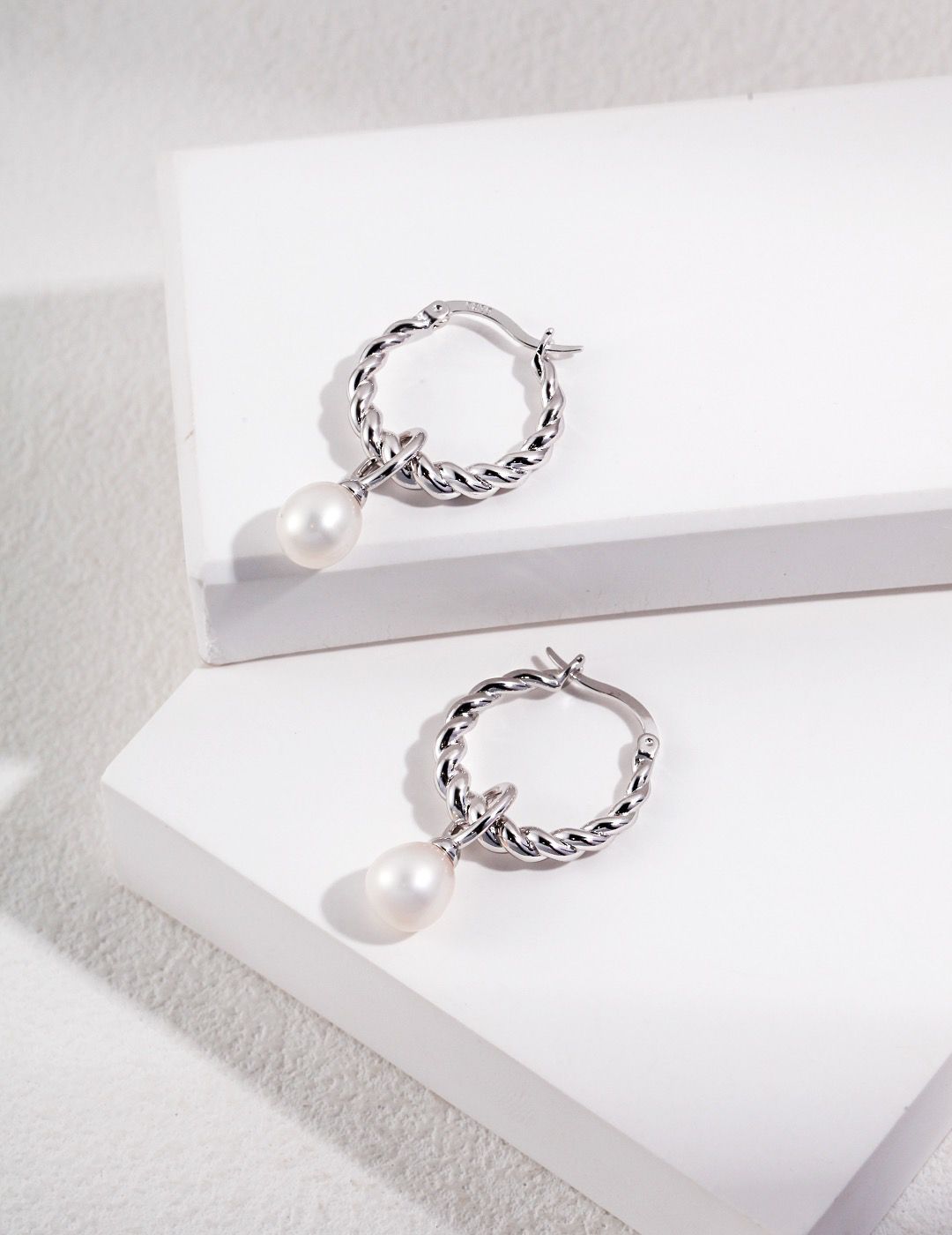 A close-up photo of Pearl Hoop Earrings on a white background.